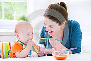 Sweet baby boy eating his first solid food with his mother