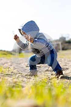 Sweet baby boy in hoodie and jeans playing in the sand. Activity with toddler