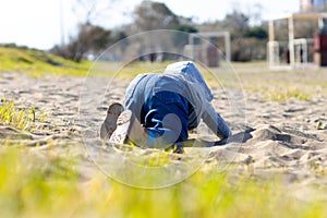 Sweet baby boy in hoodie and jeans playing in the sand. Activity with toddler
