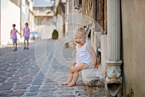 Sweet baby boy, sitting on the front porch of a house in an old part of the town, smiling happily