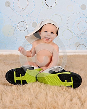 Sweet baby boy wearing large hat and sneakers