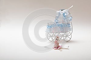 Sweet baby doll sitting in front of a baby carriage isolated o