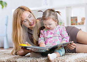 Sweet baby girl with mother reading book in nursery