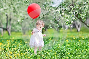 Sweet baby girl playing with a big red balloon