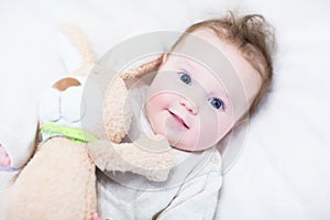 Sweet baby girl in a white round crib with pink bunny toy