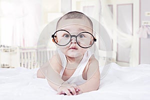 Sweet baby with glasses in bedroom