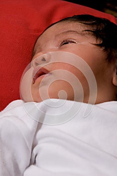 A sweet baby laying awake on red blanket