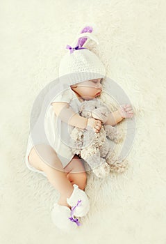 Sweet baby sleeping with teddy bear toy on white soft bed home