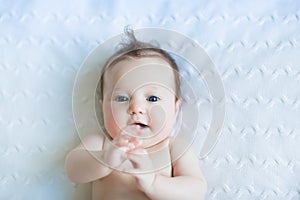 Sweet baby on a white blanket playing with its hands