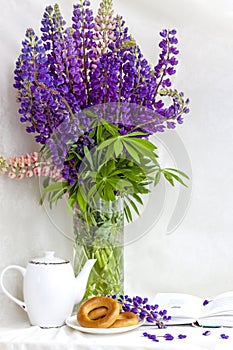 Sweet bagels and tender lupine flowers. Light composition with bright and purple flowers. A gentle and romantic morning with tea a
