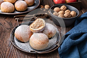 Sweet baked buns with apple and walnut filling, sprinkled with powdered sugar