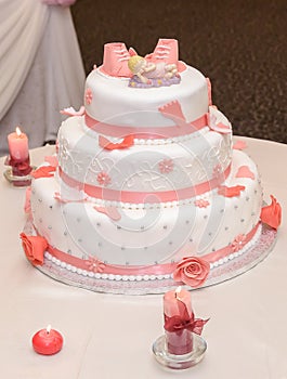 Sweet baptize cake with pink sugar shoes and burning candles