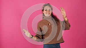 Sweet and beautiful girl in a chocolate sweater energetic and great dancer, isolated, pink background