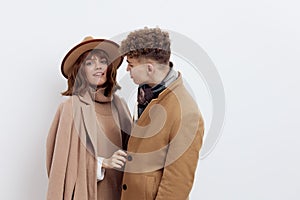 a sweet, beautiful, loving couple stands on a white background in stylish autumn clothes, gently cuddling up to each