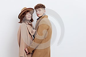 a sweet, beautiful, loving couple stands on a white background in stylish autumn clothes, gently cuddling up to each