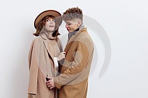 a sweet, beautiful, loving couple stands on a white background in stylish autumn clothes, gently cuddling up to each