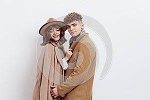 a sweet, beautiful, loving couple stands on a white background in stylish autumn clothes, gently cuddling up to each