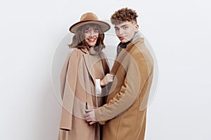 a sweet, beautiful, loving couple stands on a white background in stylish autumn clothes, gently cuddling up to each