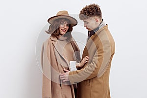 a sweet, beautiful, loving couple stands on a white background in stylish autumn clothes, gently cuddling up to each