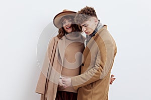 a sweet, beautiful, loving couple stands on a white background in stylish beige autumn clothes, gently cuddling up to