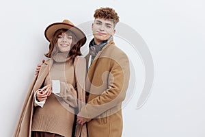 a sweet, beautiful, loving couple stands on a white background in stylish beige autumn clothes, gently cuddling up to