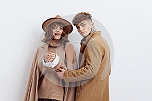 a sweet, beautiful, loving couple stands on a white background in stylish beige autumn clothes, gently cuddling up to