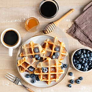 Sweet belgian waffles with blueberries, honey and cup of black coffee