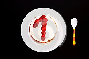 Sweet birthday cake with strawberries and number one on a white plate