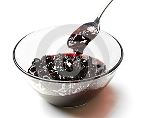 Sweet blackberry jam in the transparent glass bowl with tea spoon