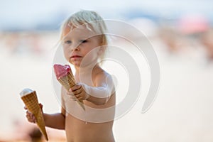 Sweet blonde toddler boy, eaiting ice cream on the beach