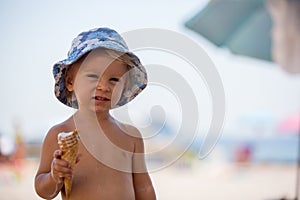 Sweet blonde toddler boy, eaiting ice cream on the beach