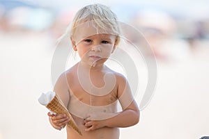Sweet blonde toddler boy, eaiting ice cream on the beach