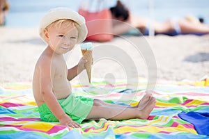 Sweet blonde toddler boy, eaiting ice cream on the beach