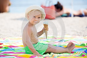 Sweet blonde toddler boy, eaiting ice cream on the beach