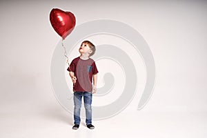 Sweet boy holding red heart balloon. Valentines day or kids healthcare, medical concept