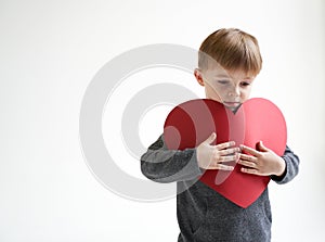 Sweet boy holding red paper heart on white background. Valentines day or kids healthcare, medical concept