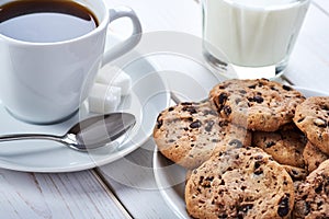 Sweet breakfast with chocolate cookies, cup of black coffee and glass of milk
