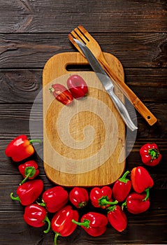 Sweet bulgarian red peppers, cutting board and knife on a dark w
