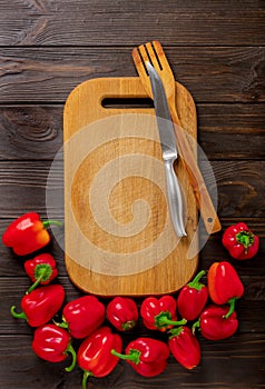 Sweet bulgarian red peppers, cutting board and knife on a dark w