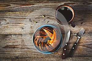 Sweet bun and cup of black coffee on vintage wooden table