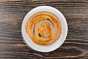 Sweet bun in white plate on dark wooden table