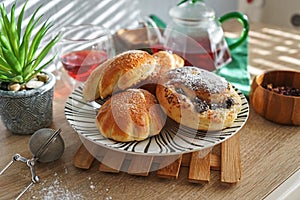 Sweet buns on a plate and hibiscus tea on a wooden table with natural light