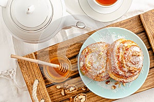 Sweet buns with walnuts, grated coconut and honey on a wooden tray. Breakfast concept. Top view