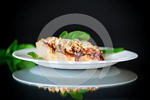 Sweet cake with fruit jam in a plate on a black