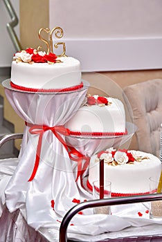 Sweet cakes in the form of red roses decorate the wedding cake with more decorative twigs of white cream