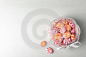 Sweet candies in glass jar on light grey table, flat lay. Space for text