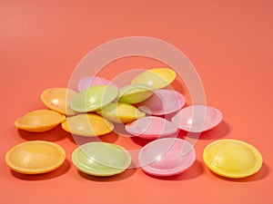Sweet candies in the shape of a UFO in different colors on a pink background.