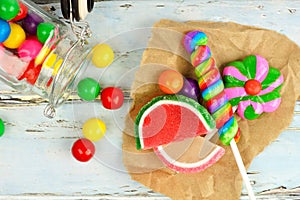 Sweet candies and spilling jar with rustic wood background