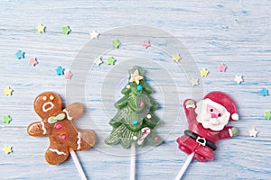 Sweet candies on a stick in shapes of Christmas tree, Gingerbread man and Santa Claus, Christmas concept on a wooden background