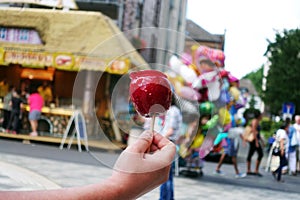 Sweet candy apple on county fair or festival. red candy apple covered in red caramel, at holiday vacation event or amusement park